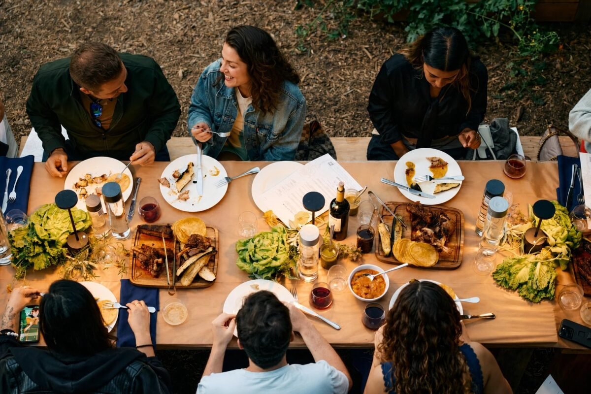Overhead view of a shared table mid-meal, plates and hands