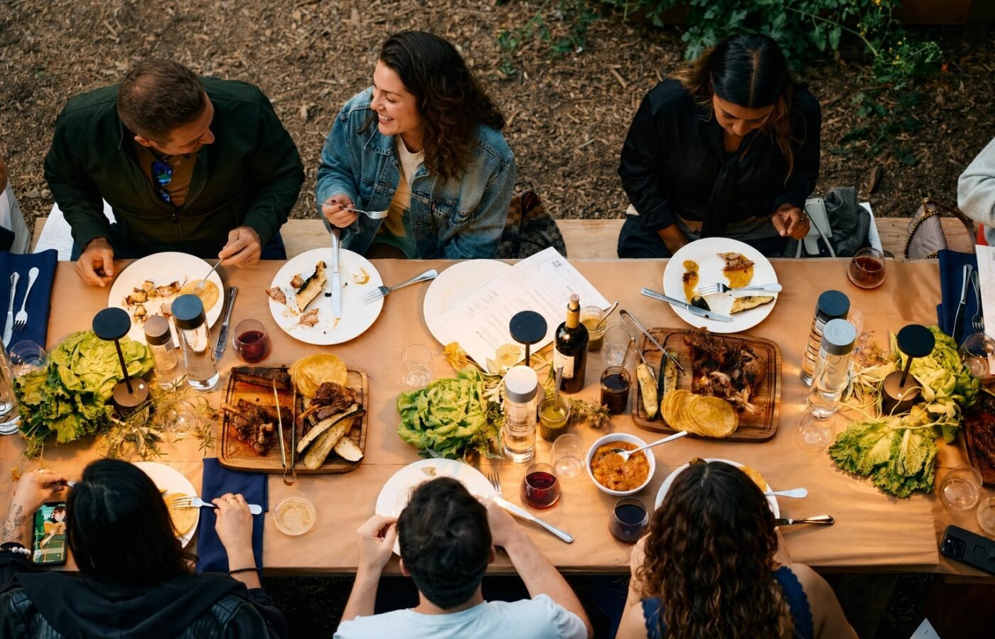 Overhead view of a shared table mid-meal, plates and hands